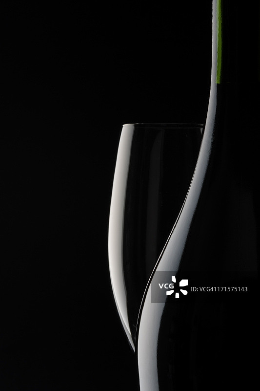 黑色背景下的空香槟酒杯和空白酒瓶图片素材