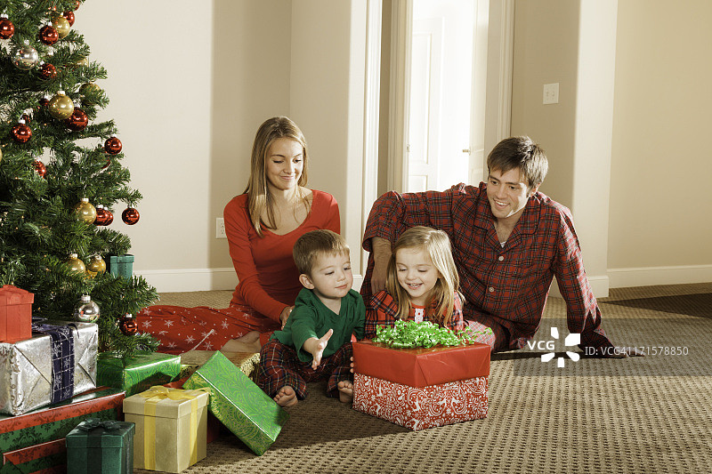 圣诞礼物早晨的兴奋，小女孩、男孩和家人打开礼物图片素材