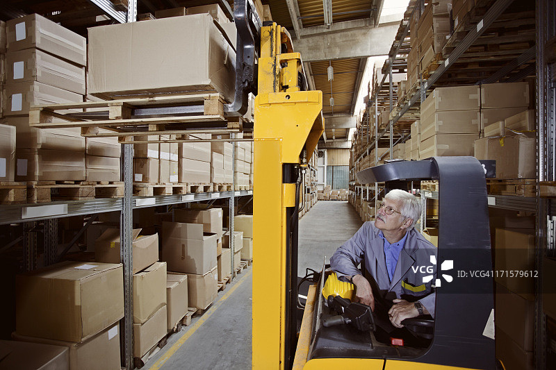 仓库叉车操作员装载纸板箱图片素材