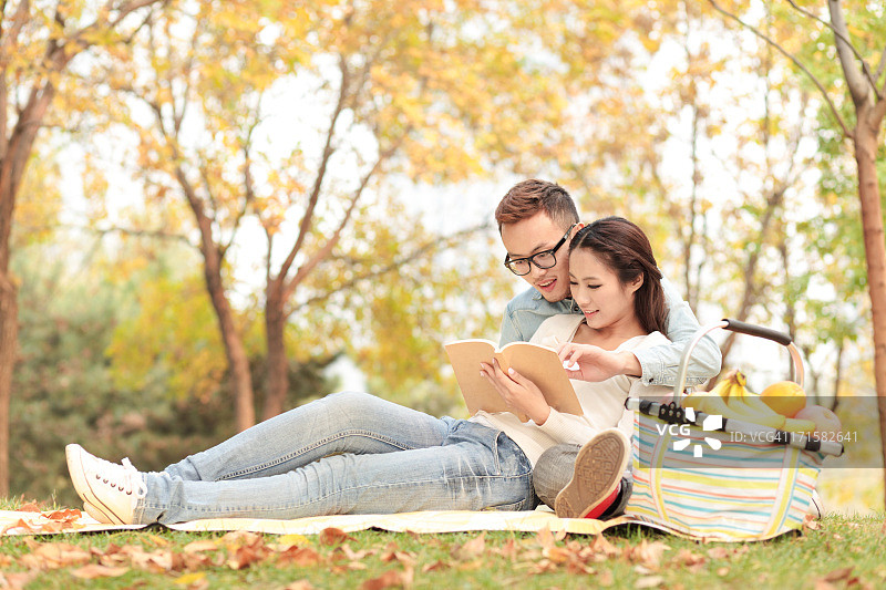 年轻情侣在公园里阅读书籍图片素材