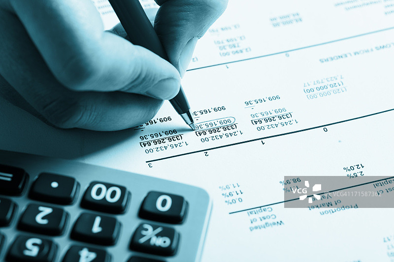 男人手部用圆珠笔圈出财务文件上的数字图片素材