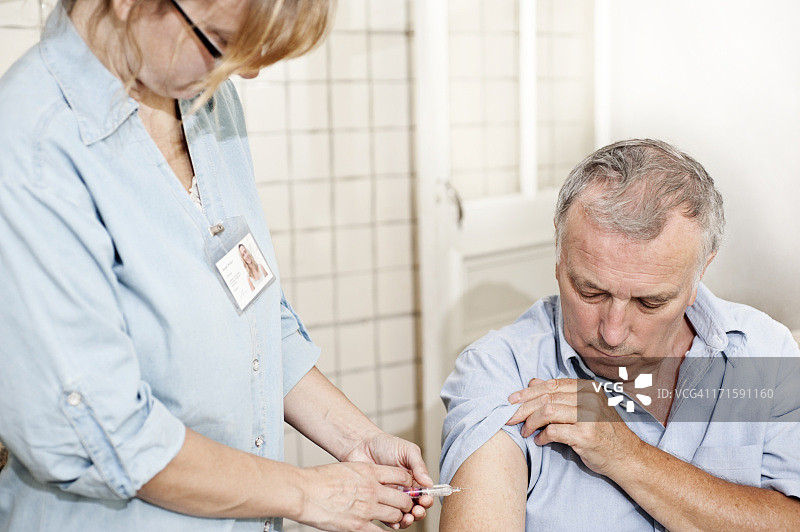 男人卷起袖子接受护士的疫苗接种图片素材