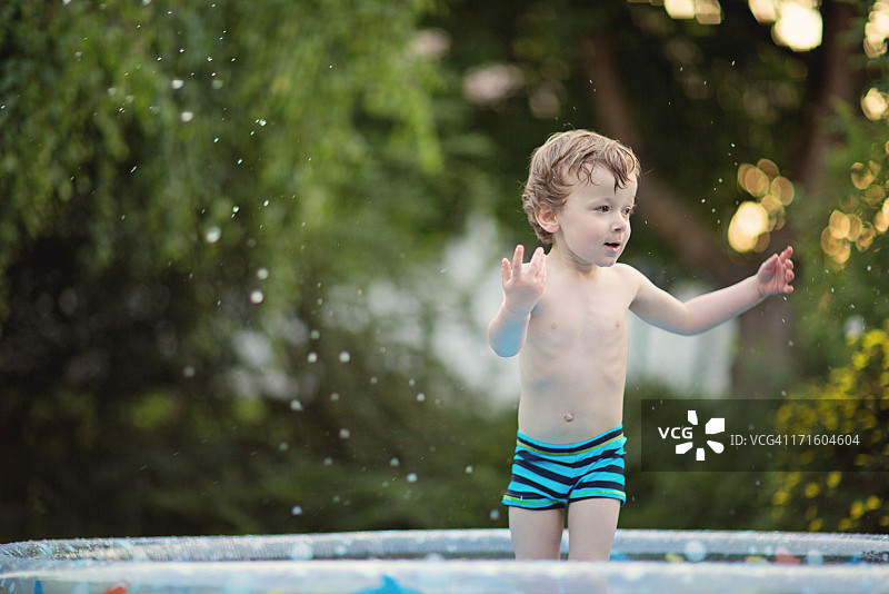 儿童站在浅水池中泼水图片素材