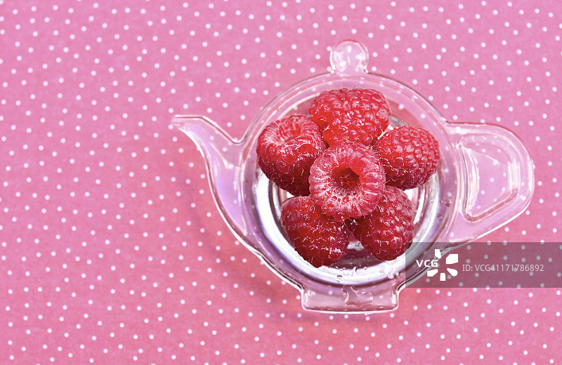 茶壶形盘子上的覆盆子图片素材