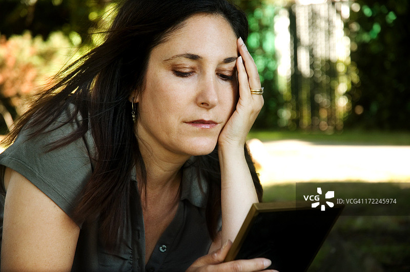悲伤地看着照片的女人图片素材
