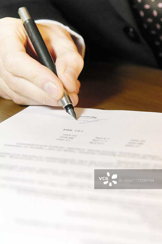 商务人士在办公桌上签署文件的手部特写图片素材