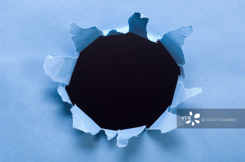 黑色背景上撕裂的纸张破洞图片素材
