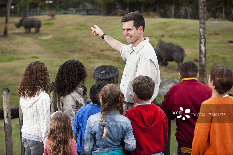 动物园管理员与一群孩子在犀牛展区图片素材