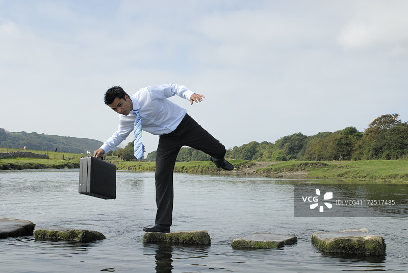 男人在池塘附近的岩石上失去平衡图片素材