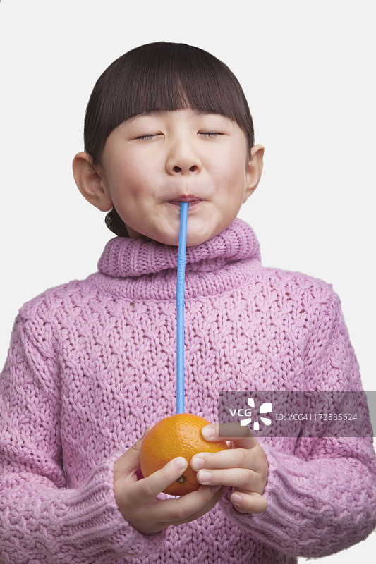 年轻女孩用吸管喝橙汁的写真图片素材