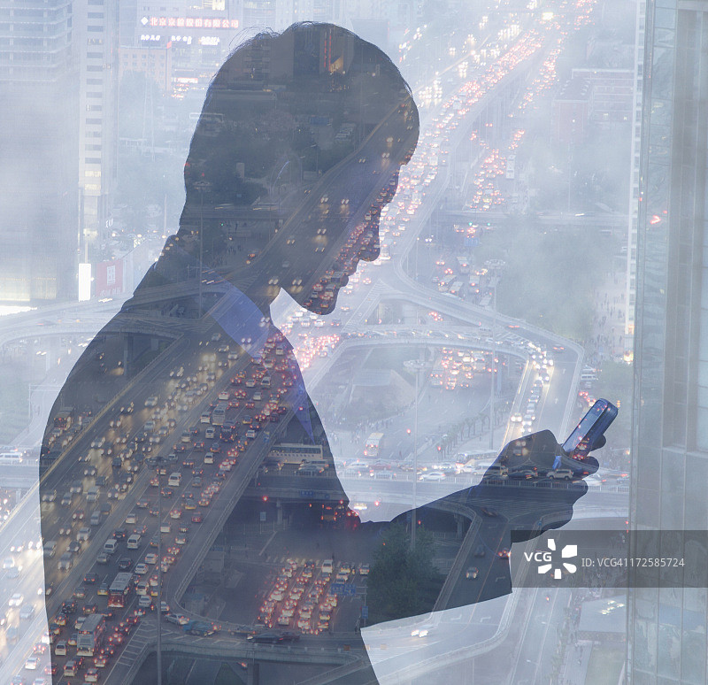 年轻商人使用手机，夜间城市交通双重曝光图片素材