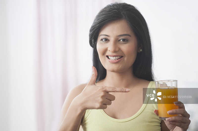 快乐的女人指向一杯橙汁图片素材