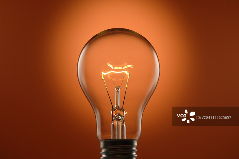橙色背景上的发光灯泡图片素材