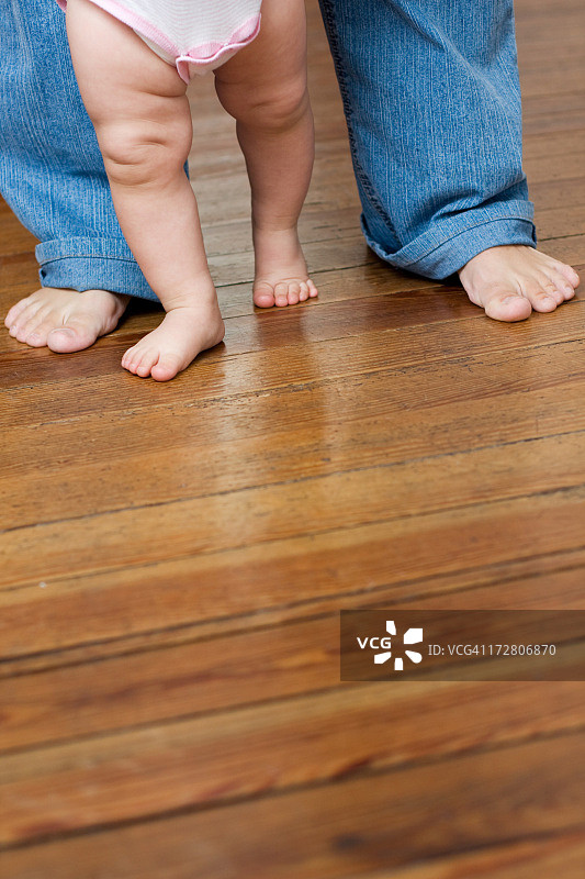 成年人帮助正在学习走路的孩子图片素材