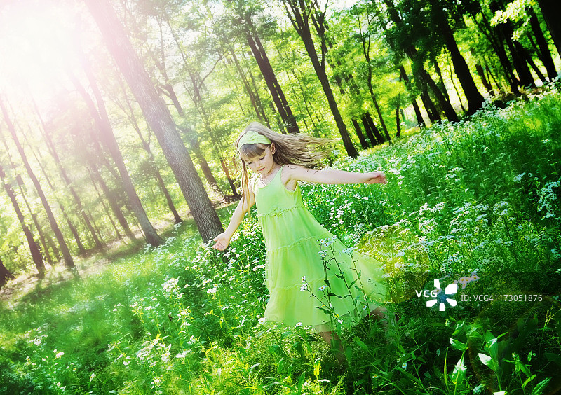 在春日绿色田野阳光下跳舞的年轻女孩图片素材