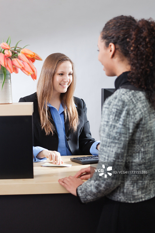 友善的银行柜员在柜台窗口帮助客户图片素材