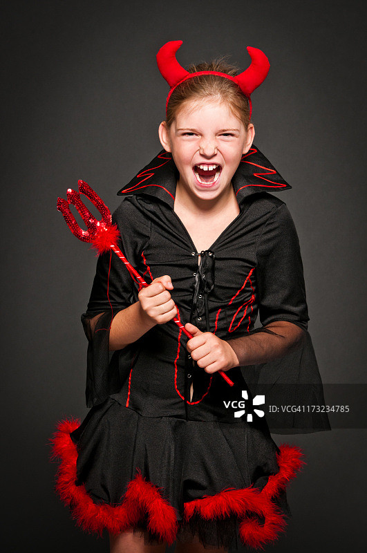 穿魔鬼服装的女孩大笑尖叫，黑色背景图片素材