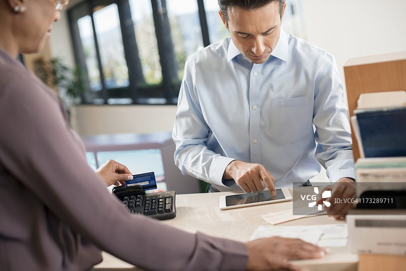 顾客在银行柜台使用借记卡图片素材