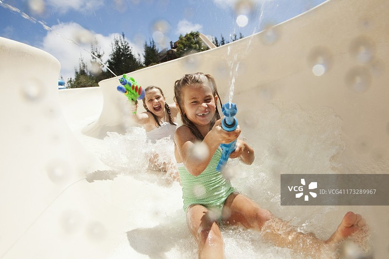 儿童（8-12岁）拿着水枪滑下水滑梯图片素材