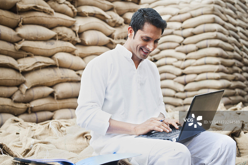 印度哈里亚纳邦古尔冈索赫纳谷物市场使用笔记本电脑的男人图片素材