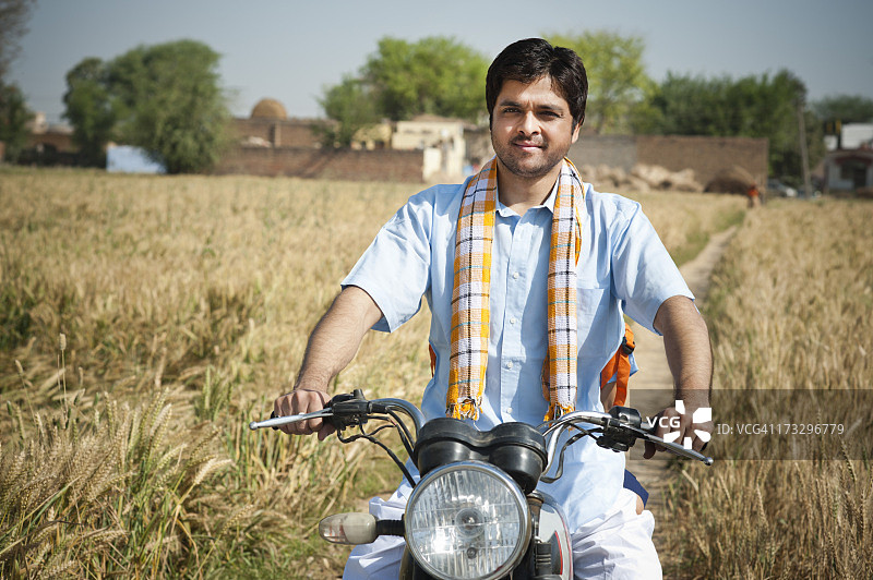 农民在印度哈里亚纳邦索赫纳的田野里骑摩托车图片素材