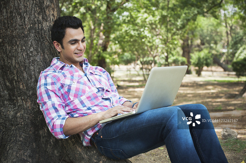 男人在印度德里洛迪花园的公园里使用笔记本电脑图片素材