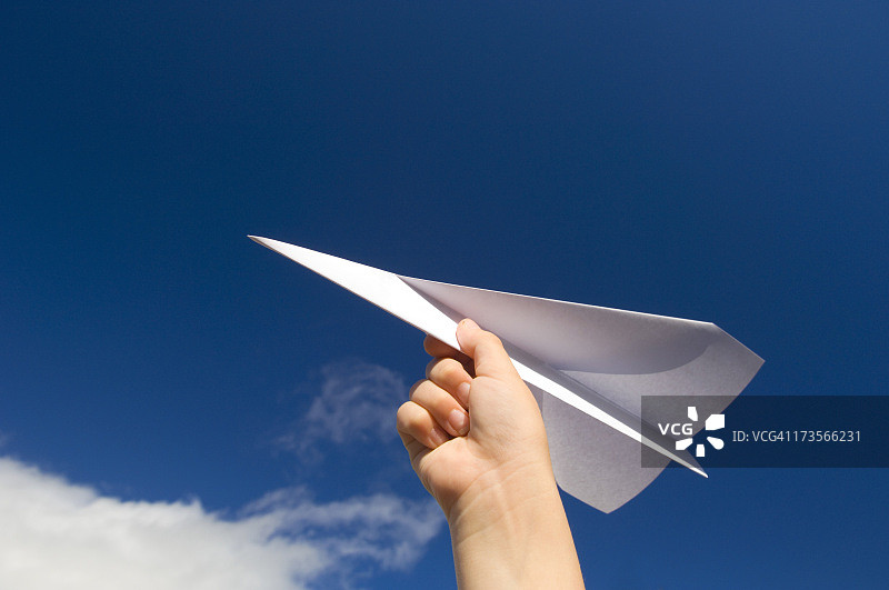 手持纸飞机，天空背景图片素材