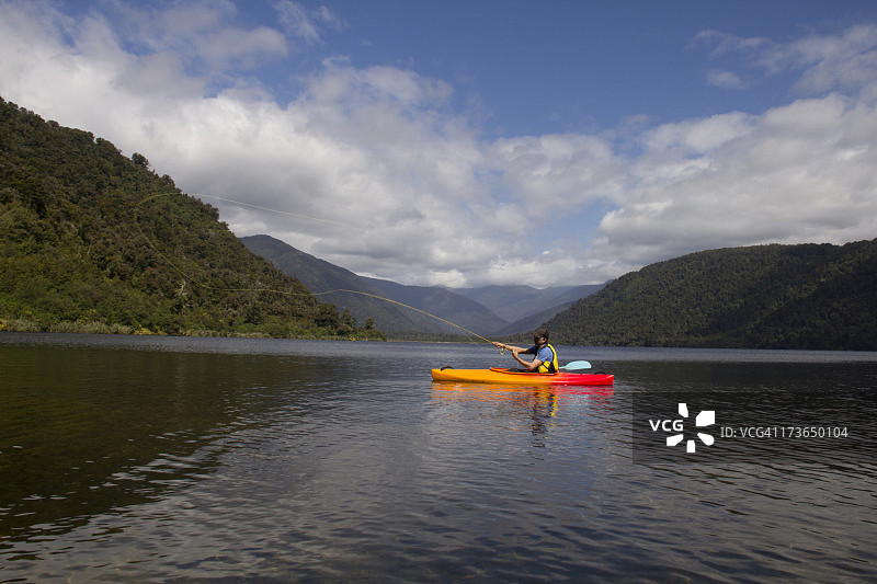 男人在新西兰的独木舟上飞蝇钓鱼图片素材