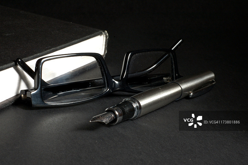 黑色书籍和笔旁边的黑色眼镜特写图片素材