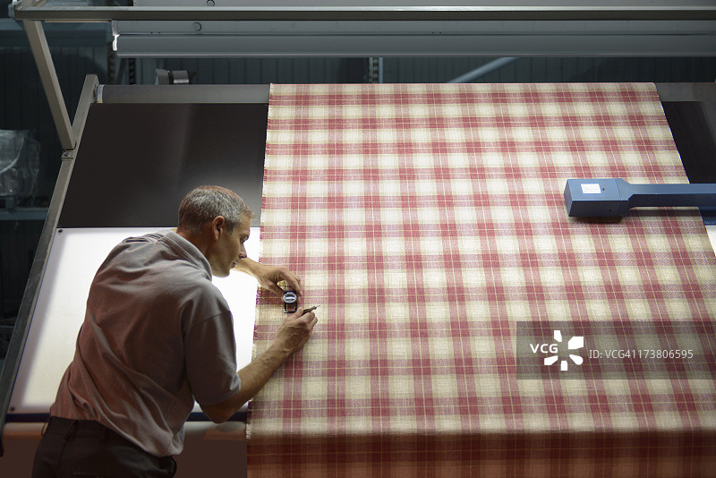 纺织工人在工厂检查格子布纹线的高角度视图图片素材