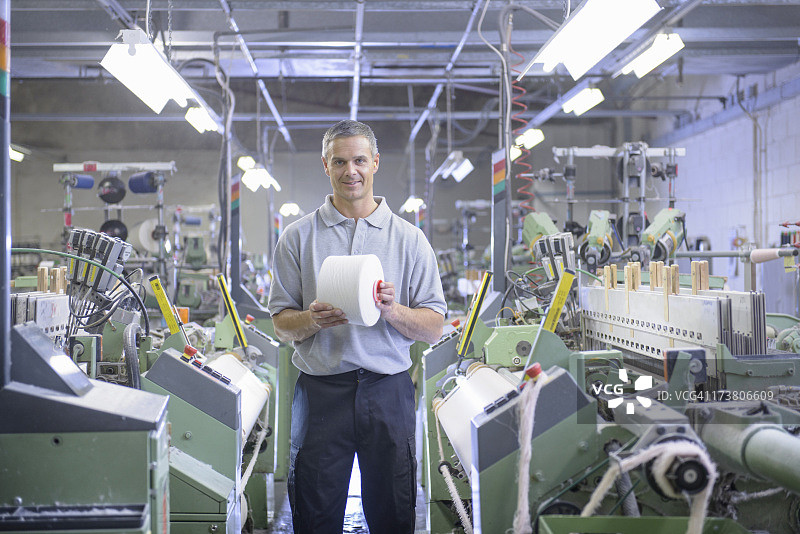 纺织女工在纺织机旁手持线轴的肖像图片素材