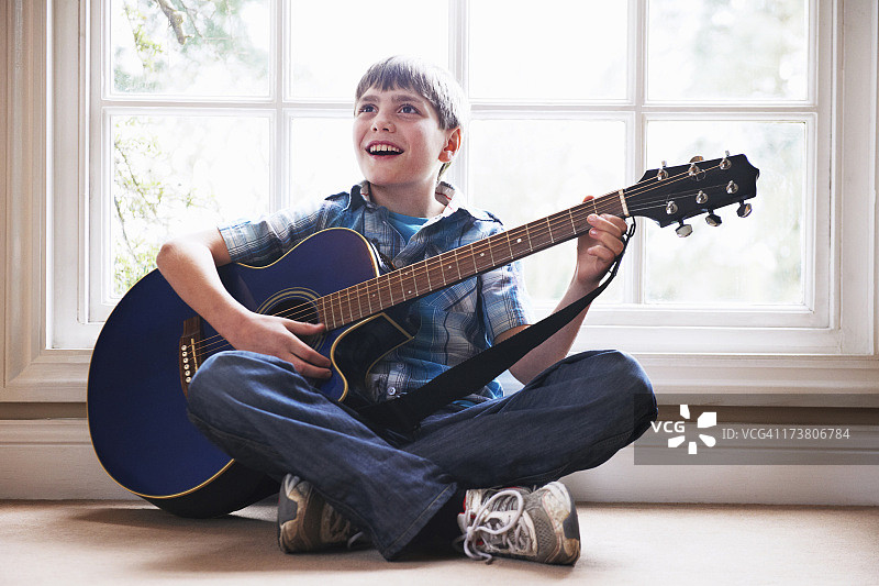 男孩在地板上弹吉他图片素材