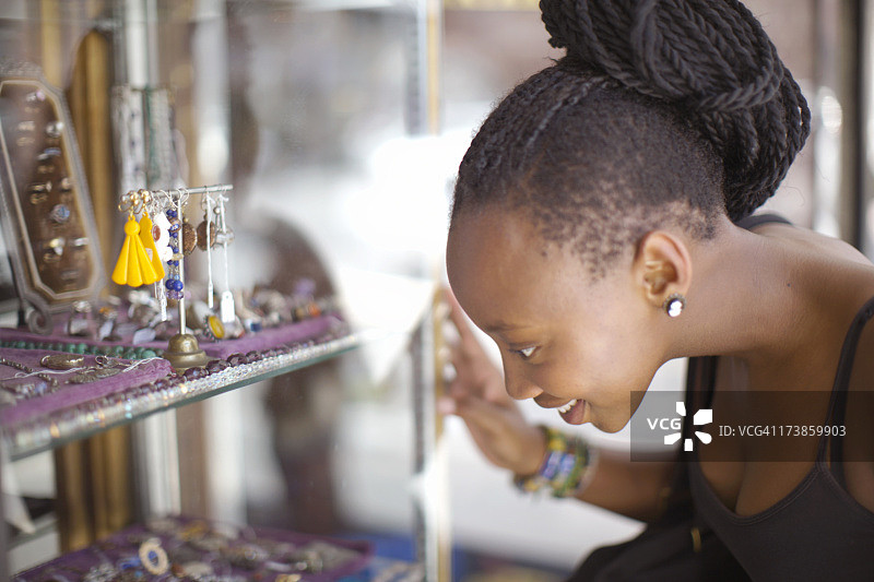 年轻女子透过珠宝店的窗户向外看。南非西开普省开普敦图片素材