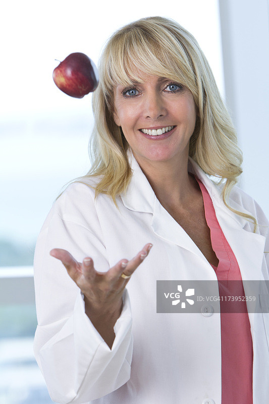 穿实验服的女人将苹果抛向空中图片素材