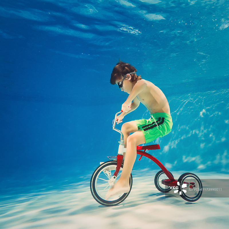 男孩在水下骑三轮车图片素材