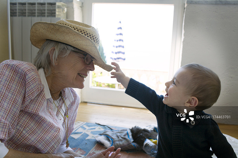 男婴抓住祖母的帽子图片素材
