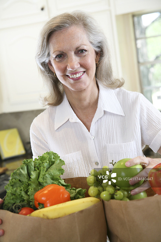 拿着食品袋微笑的家庭主妇图片素材