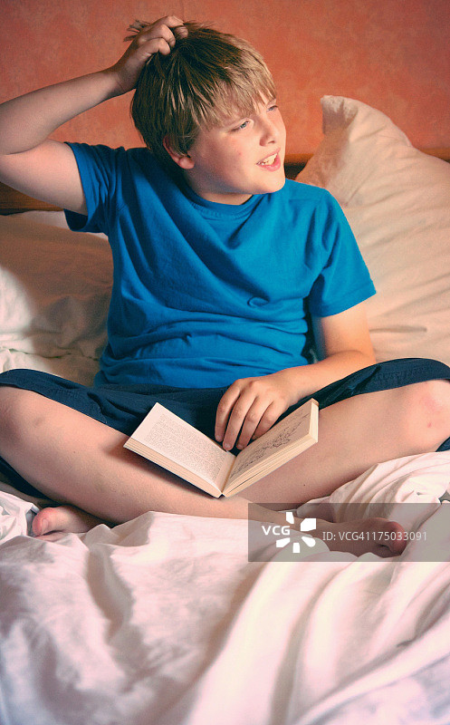 男孩拿着书，挠头思考图片素材