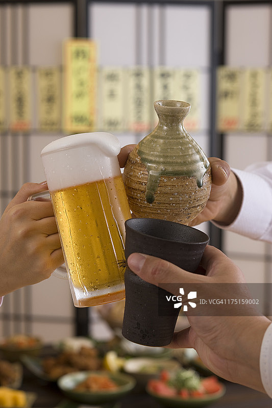 在日式酒吧用各种饮品互相敬酒的三个人图片素材