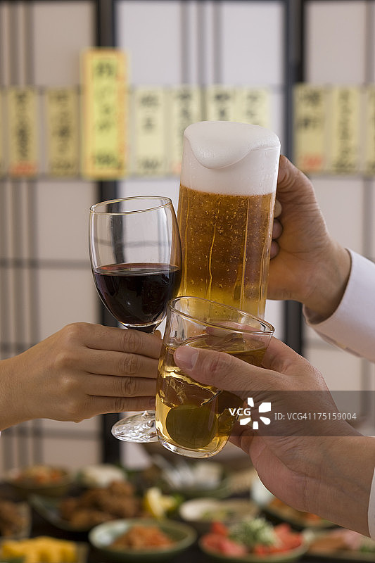 在日式酒吧用各种饮品互相敬酒的三个人图片素材