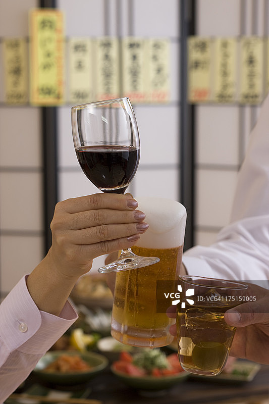 在日式酒吧用各种饮品互相敬酒的三个人图片素材