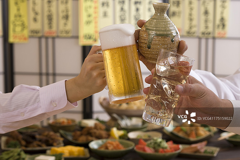 在日式酒吧用各种饮品互相敬酒的三个人图片素材