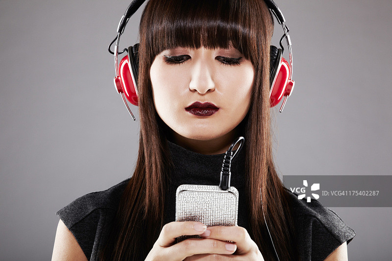 戴红色耳机听音乐的日本美丽女人图片素材