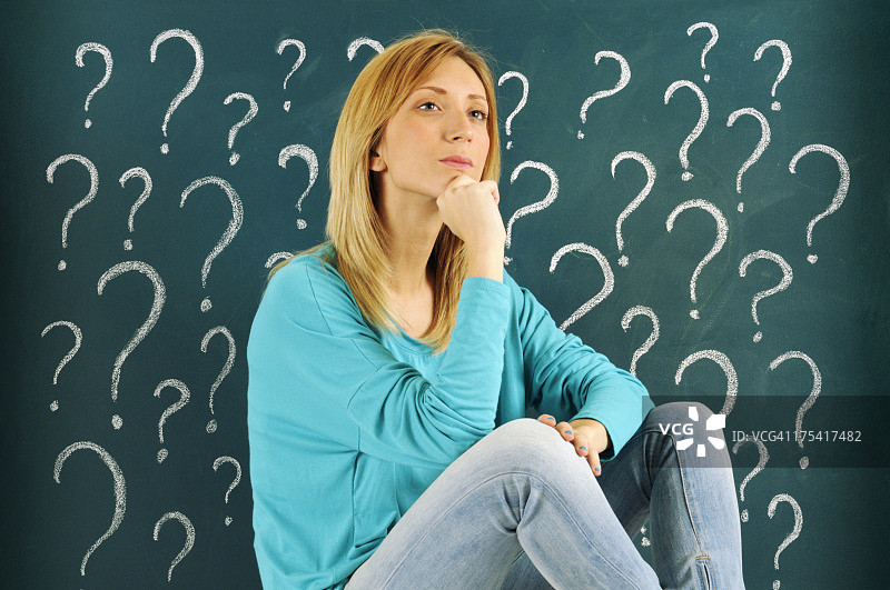 沉思的女人，黑板上画着问号图片素材