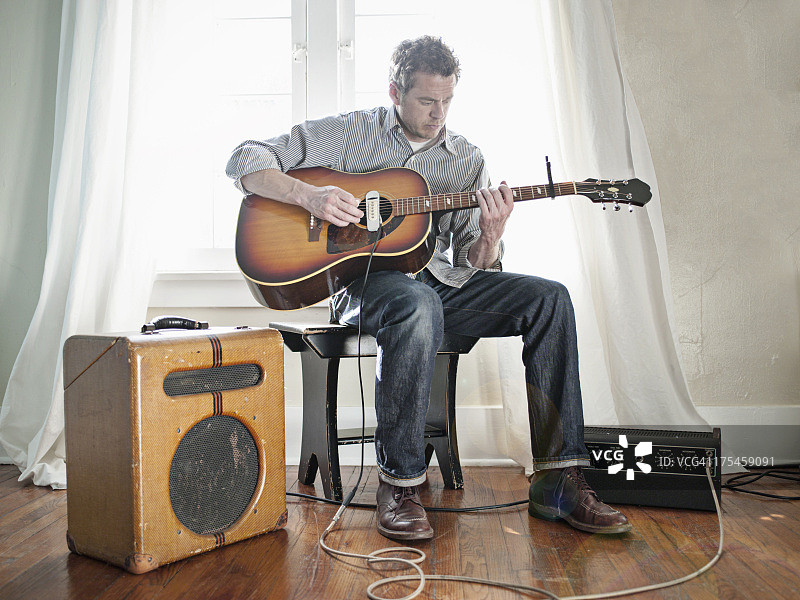 男人弹奏带电拾音器民谣吉他图片素材
