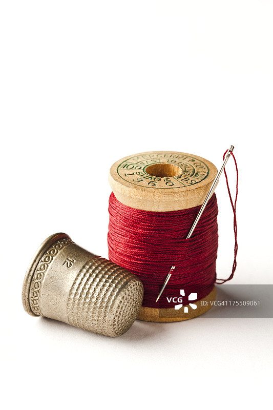 白色背景上的顶针、针和线轴图片素材