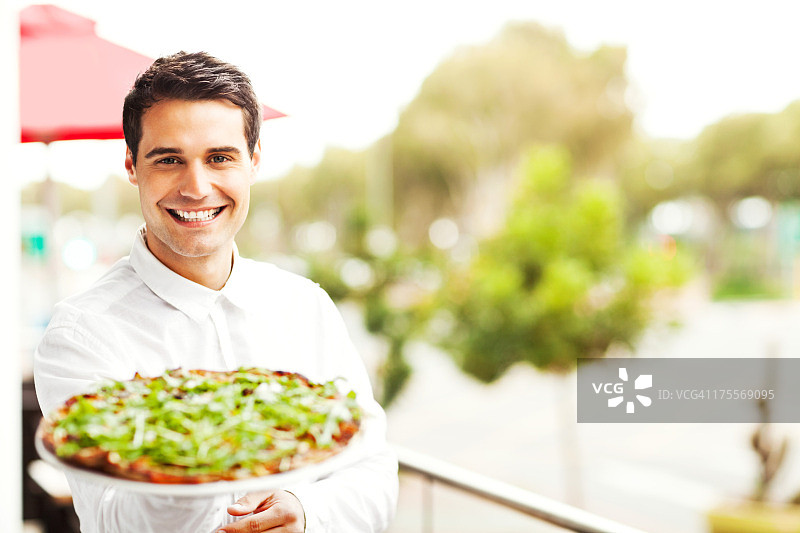 餐厅里展示披萨的快乐男服务员图片素材
