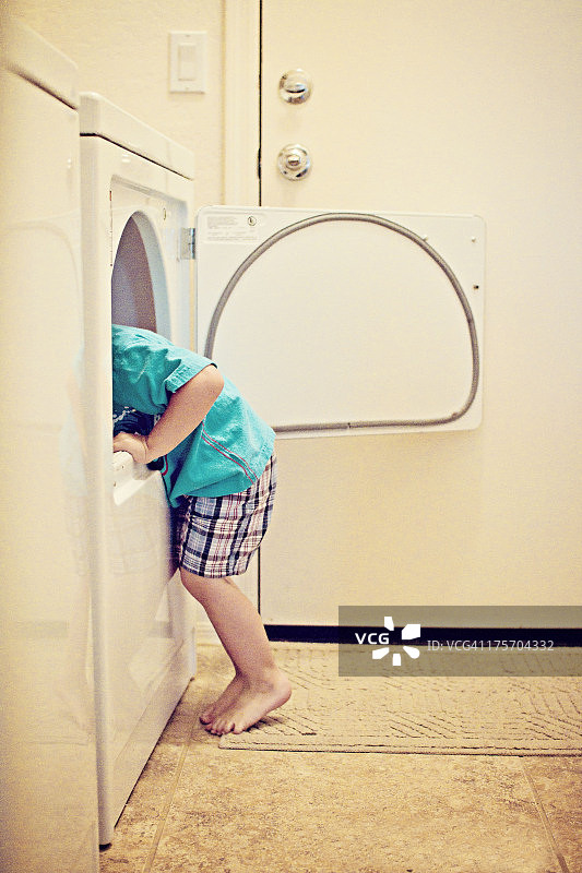 孩子帮忙把衣服放进烘干机图片素材