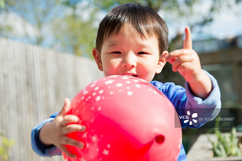 在花园里玩红色气球的男童图片素材