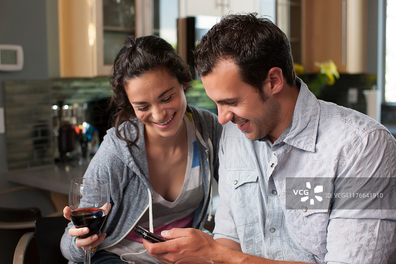 年轻夫妇举着酒杯看手机图片素材